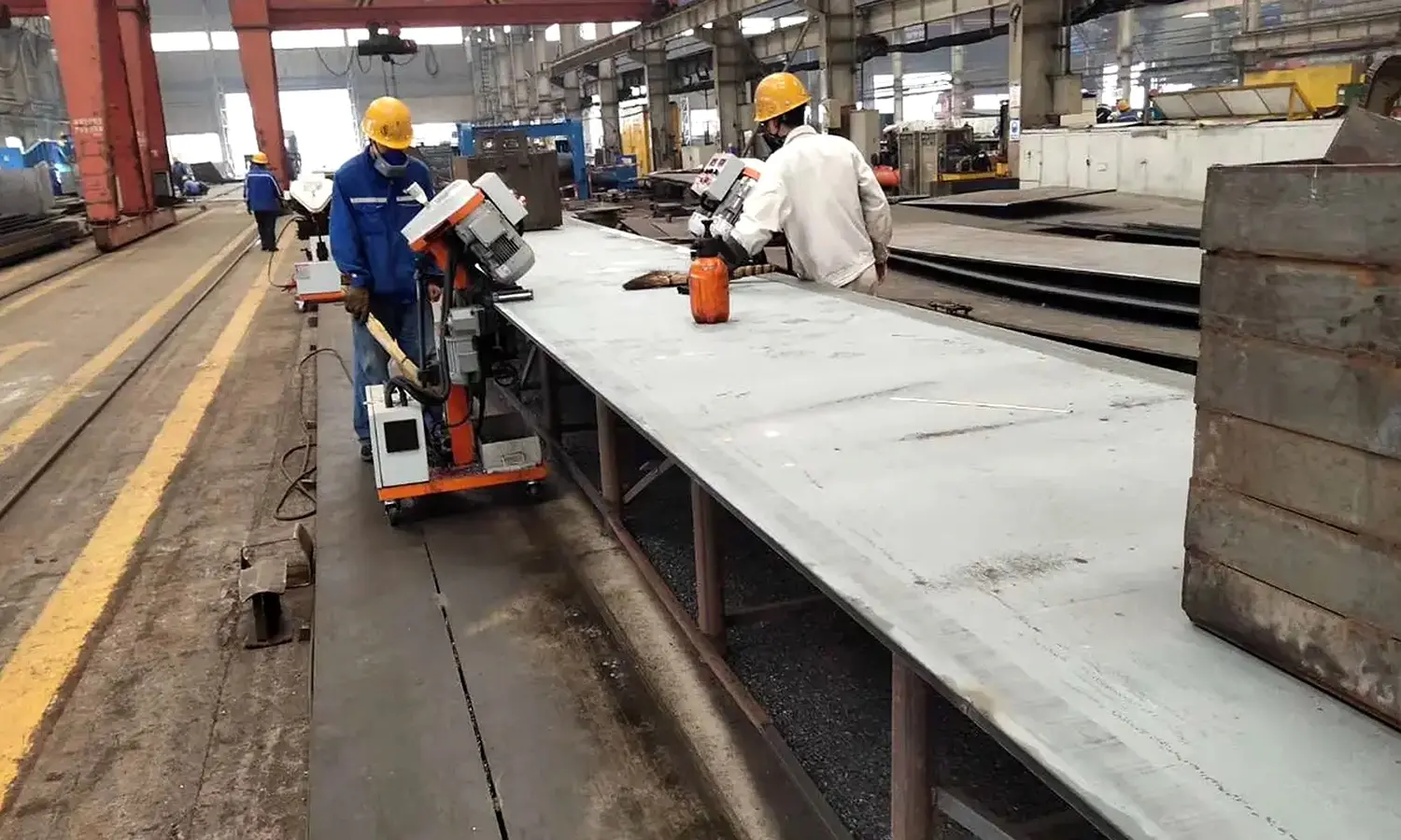 Self-propelled plate edge milling machine traveling along structural steel plate, producing clean beveled edge with metal chips