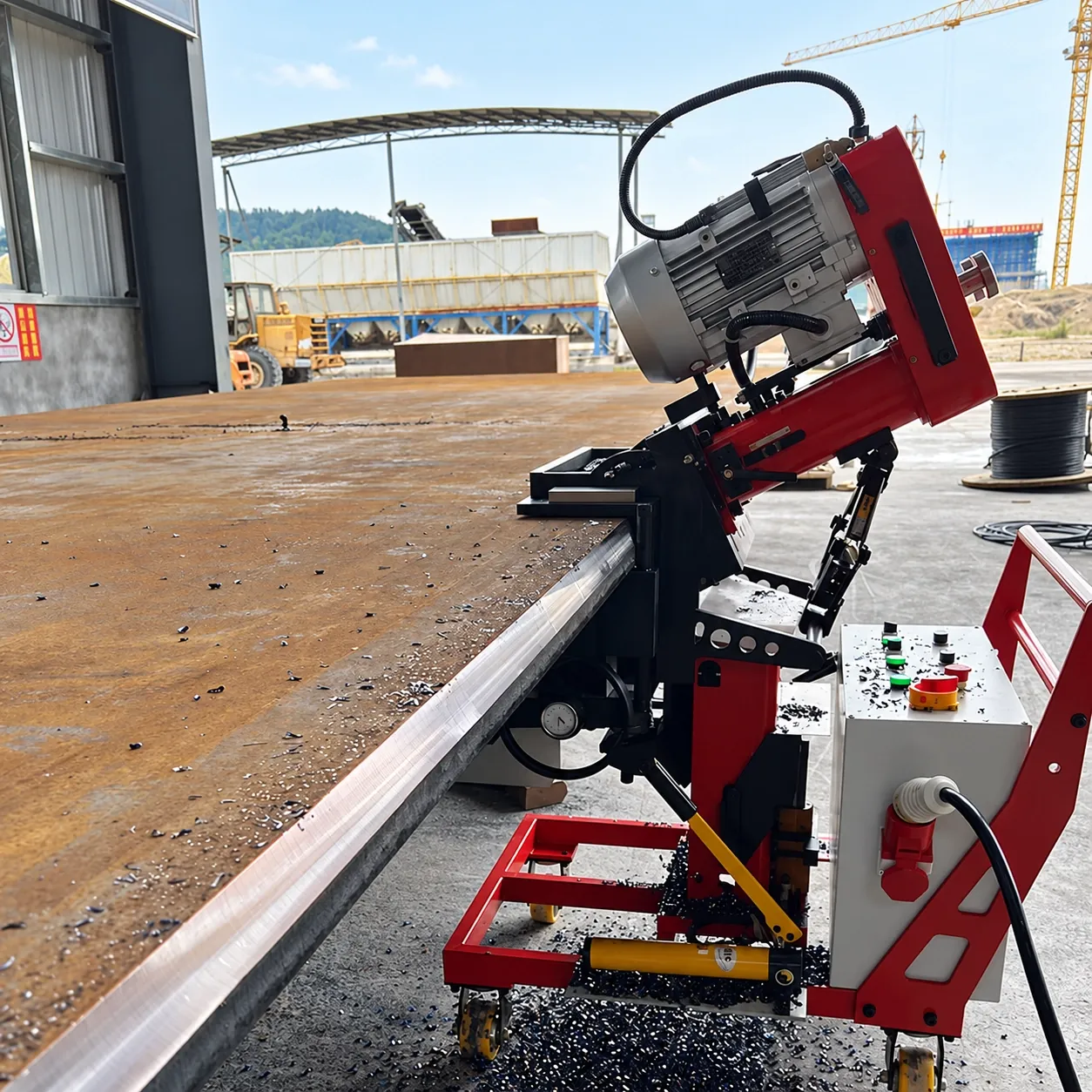 DMM-900X walking along a long steel plate edge outdoors in a fabrication yard