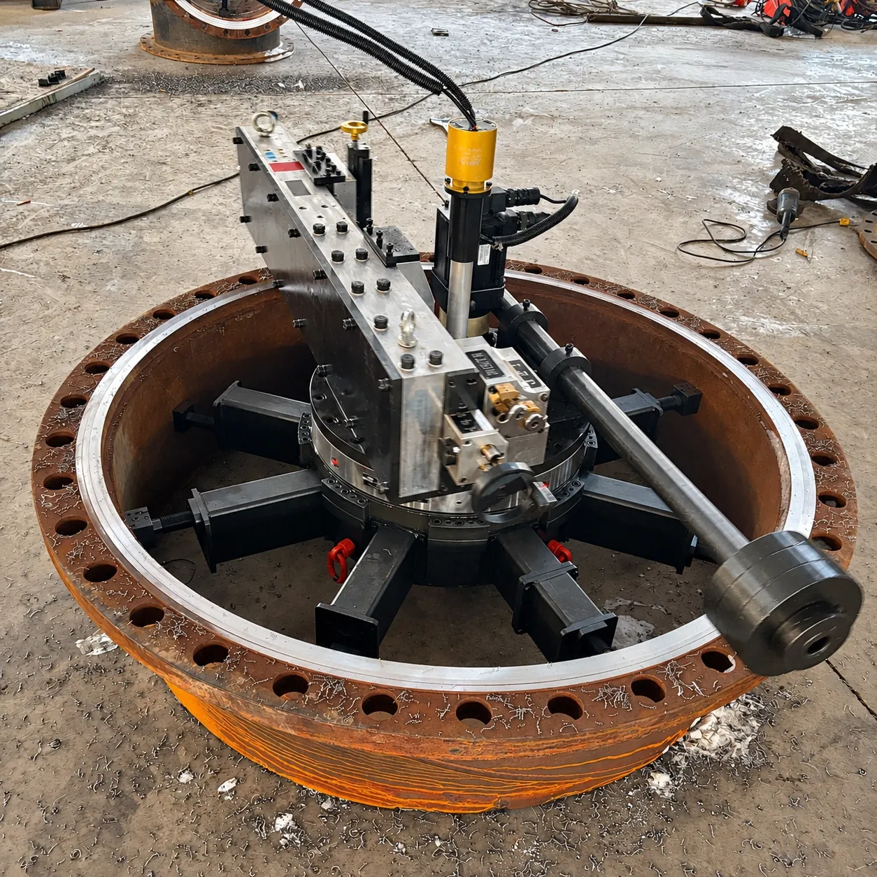 Portable flange facer centred on a large bolted flange with hydraulic drive hoses